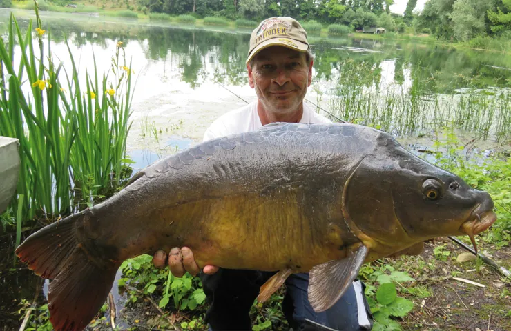 Angler hält einen großen Süßwasserfisch in beiden Händen.