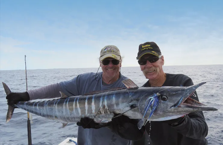 Zwei Angler auf einem Boot halten einen großen Fisch in den Händen.