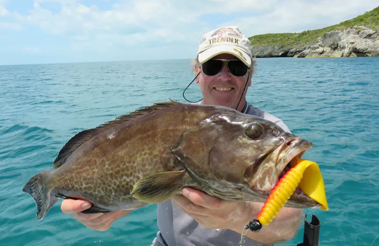 Angler auf dem Meer präsentiert stolz einen gefangenen Fisch.